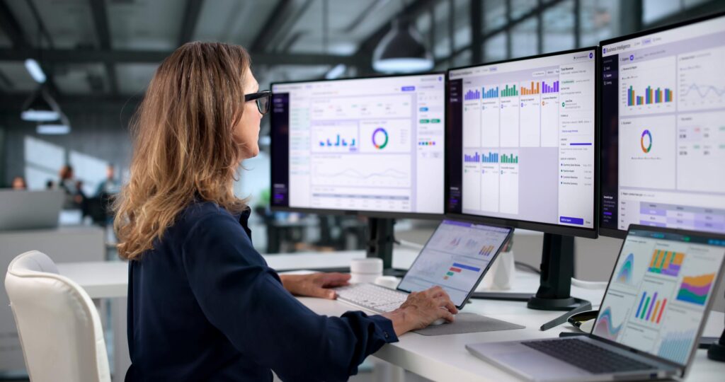 Business analyst reviewing multiple dashboards as reporting governance requirements increase
